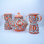 Load image into Gallery viewer, Floral Charm Tea Set by Tanutra - Hand-painted ceramic teapot and cups with vibrant orange and white floral motifs, perfect for tea rituals, home decor, and gifting. Authentic Indian craftsmanship.
